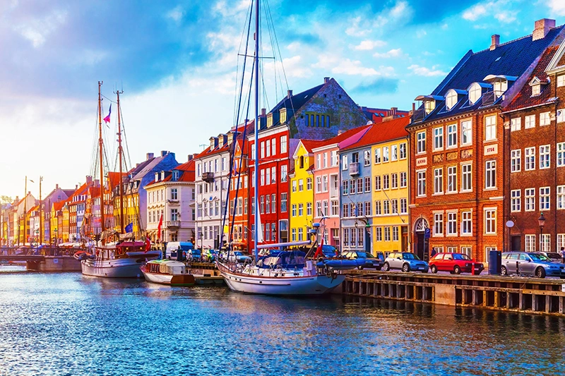 Scenic summer sunset view of Nyhavn pier with color buildings, ships, yachts and other boats in the Old Town of Copenhagen, Denmark