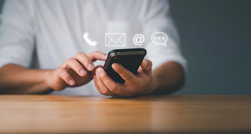 Stock Photo of man using cell phone with floating icons of phone, letter, @, and a message