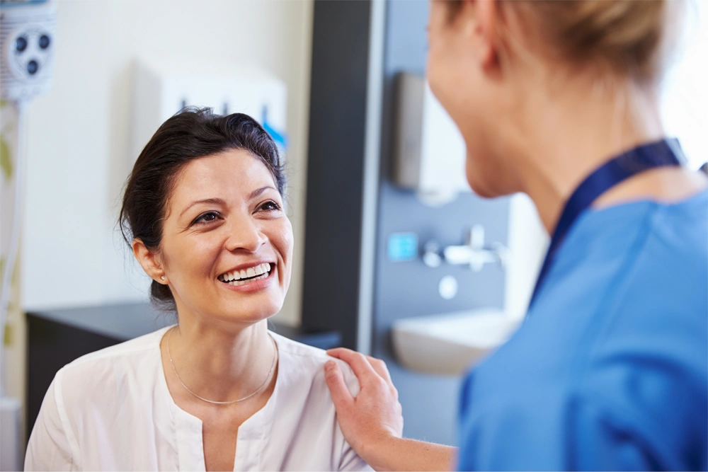 Stock Image of Female Doctor Touching smiling Female patient on shoulder reassuringly