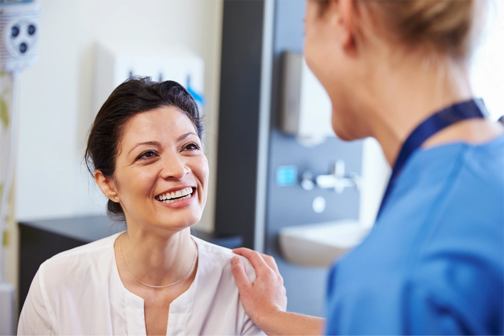 Female Doctor Touching smiling Female patient on shoulder reassuringly