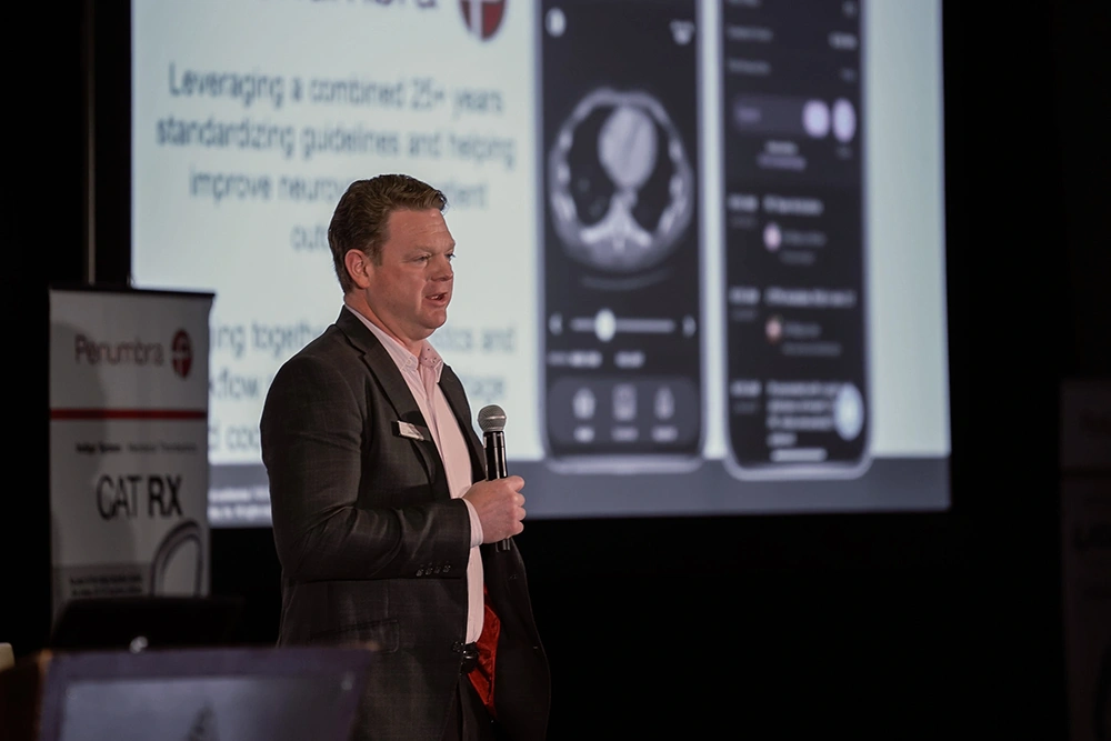 Jason Mills speaking into a microphone at a conference