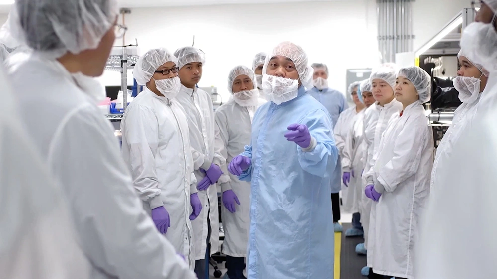 Meeting of people in lab coats, and hair nets in the engineering room