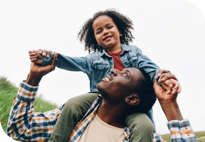 a father holding his daughter on his shoulders