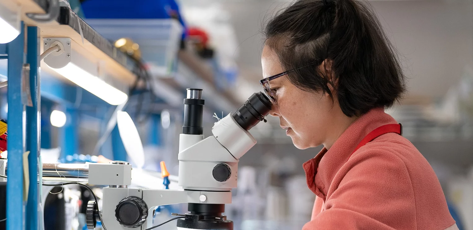 woman looking into microscope