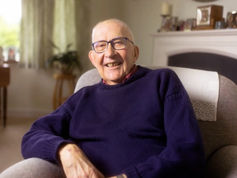 smiling Man on arm chair in purple sweater