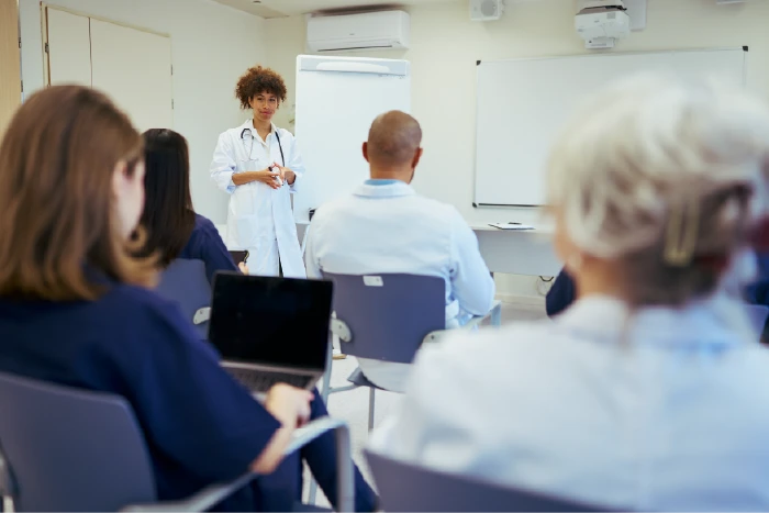 Physicians in a class room setting facing an instructor and white board