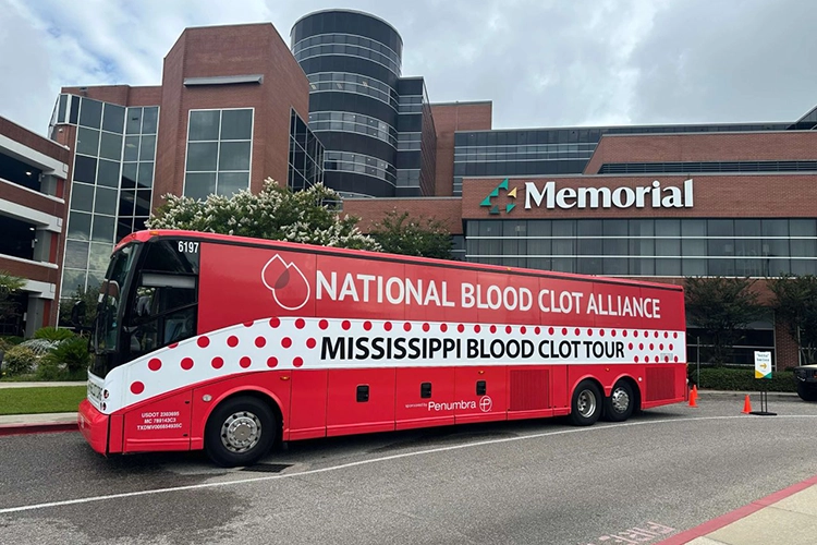 A big red bus in front of a hospital.